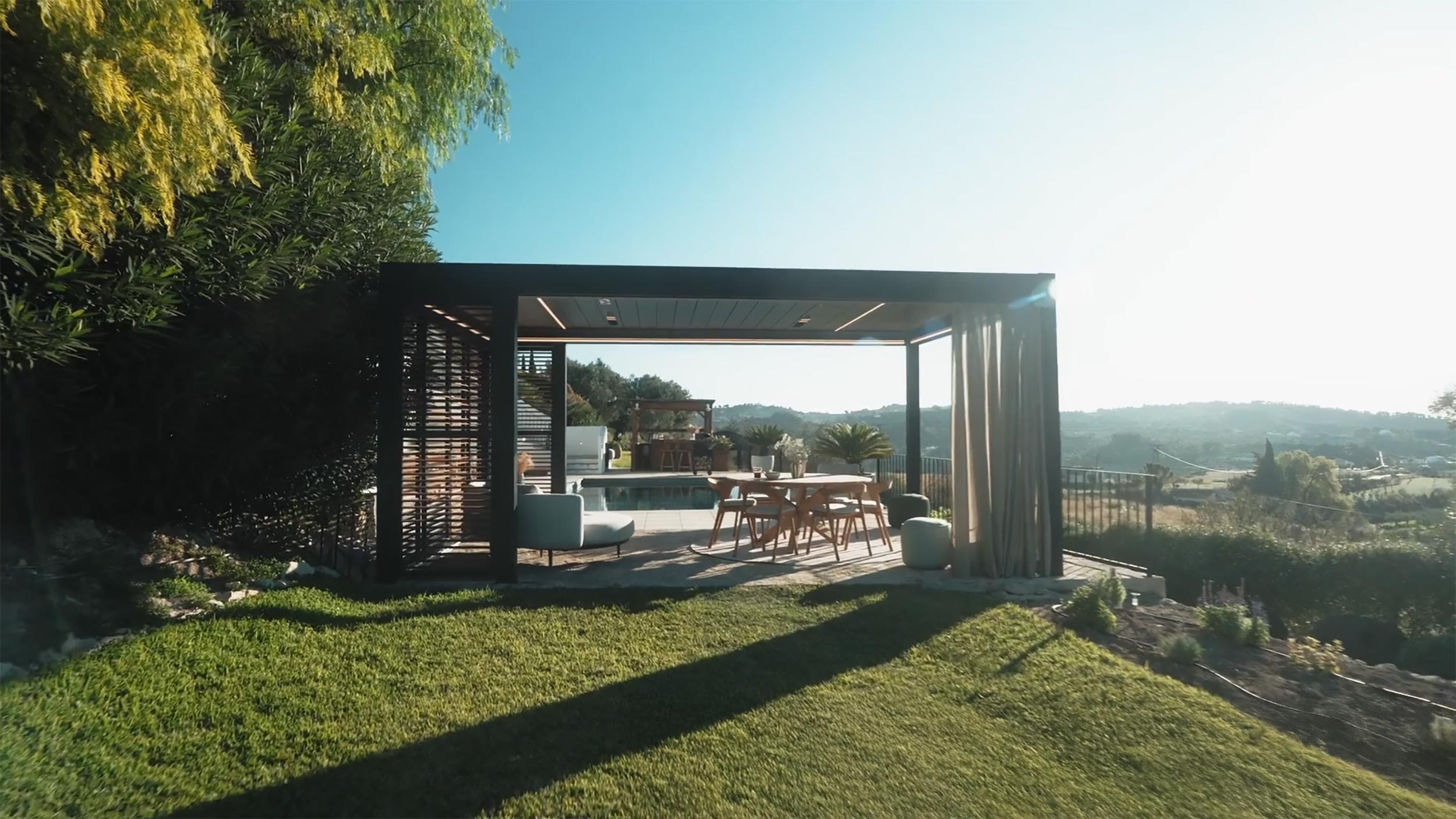Outdoor pergola with dining table, lounge seating, and pool view overlooking hills